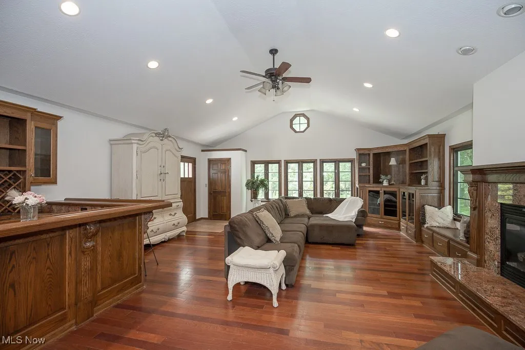 Living room featuring ceiling fan, lofted ceiling, a high end fireplace, healthy amount of natural light, and recessed lighting