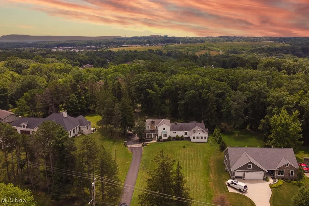 Aerial view of property and surrounding area with a heavily wooded area