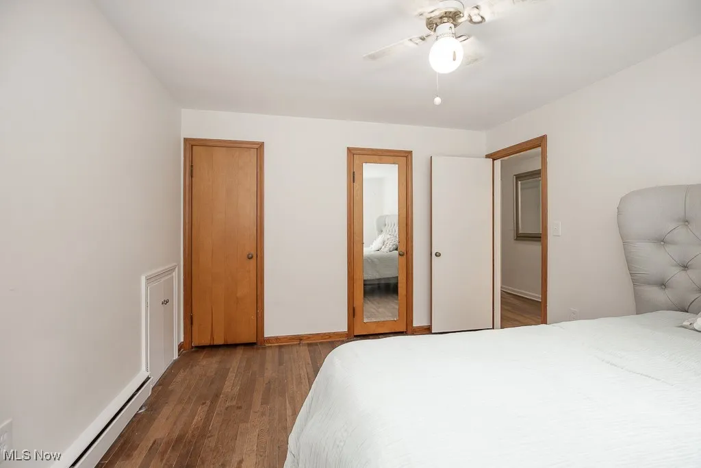 Bedroom with baseboard heating, wood finished floors, and ceiling fan