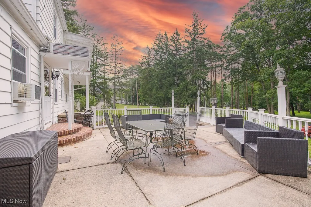 Patio terrace at dusk featuring outdoor dining area, a patio, and view of wooded area