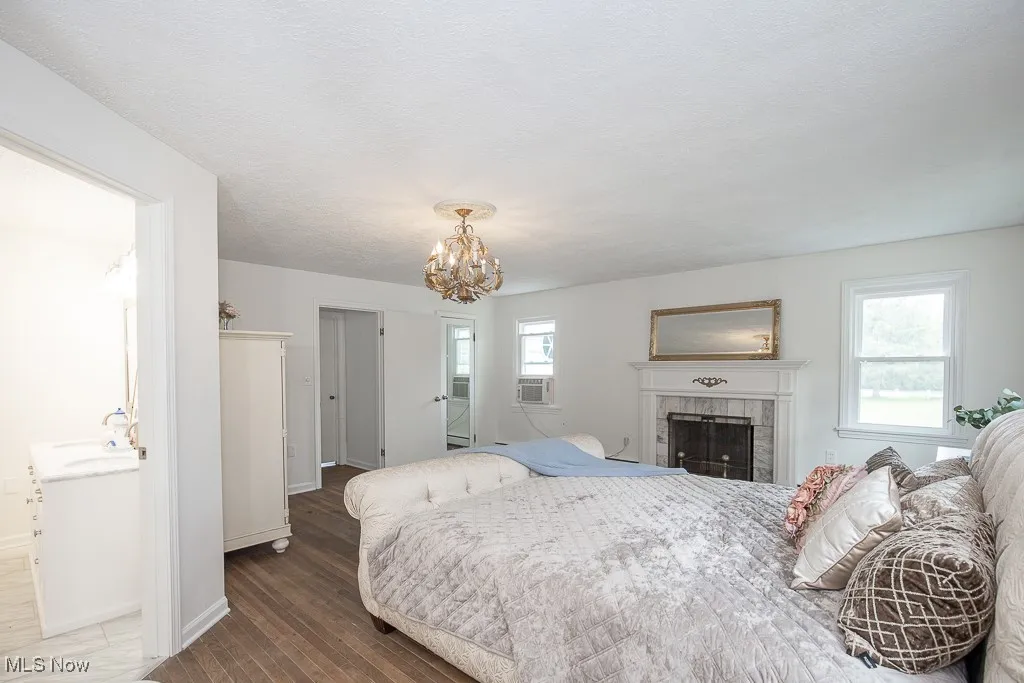 Bedroom with a chandelier, a tiled fireplace, and wood finished floors