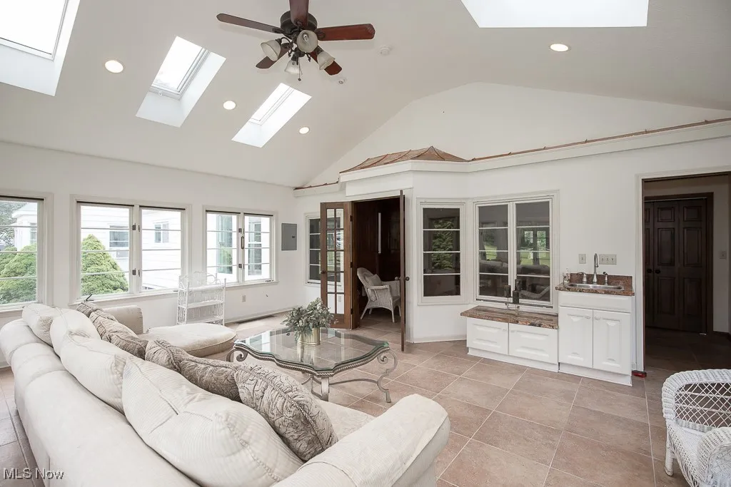 Living area with a skylight, recessed lighting, plenty of natural light, high vaulted ceiling, and a ceiling fan