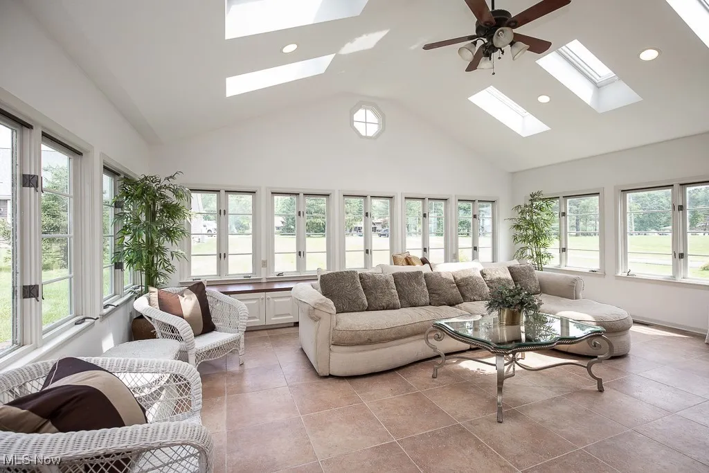 Living area with a skylight, plenty of natural light, high vaulted ceiling, recessed lighting, and light tile patterned floors