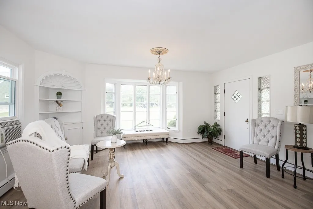 Living area featuring a chandelier, wood finished floors, cooling unit, and a baseboard radiator