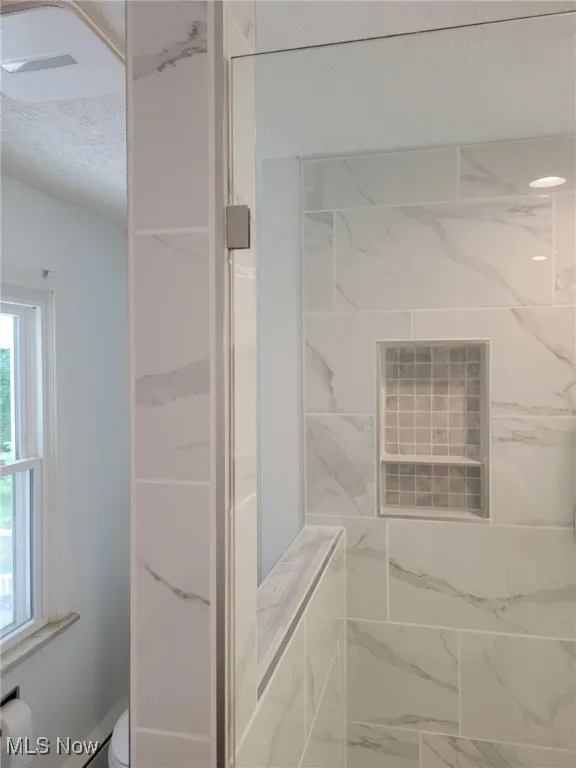 Bathroom with a shower and marble look tile flooring