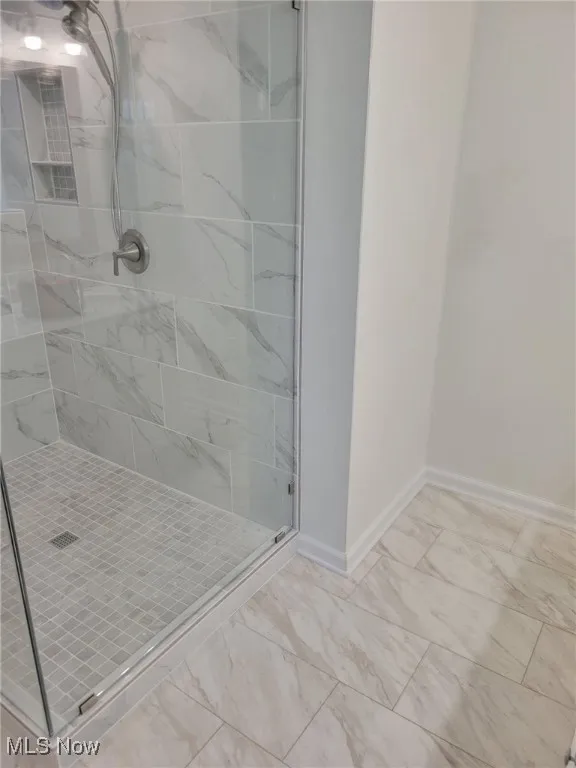Bathroom with a stall shower and marble look tiles