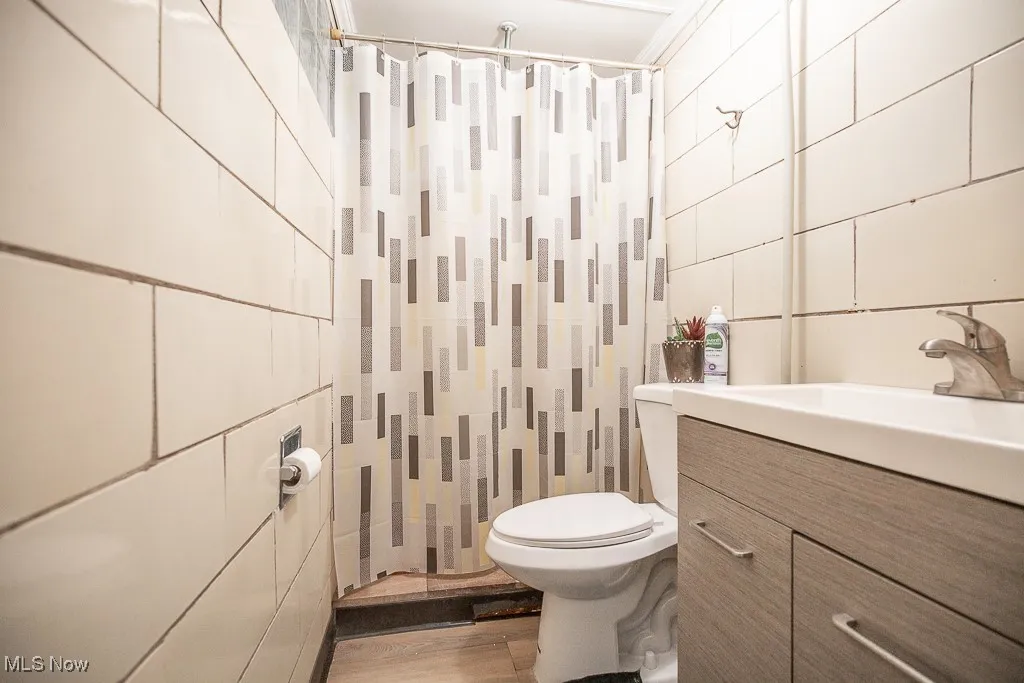 Bathroom featuring vanity, tile walls, a shower with curtain, and wood finished floors