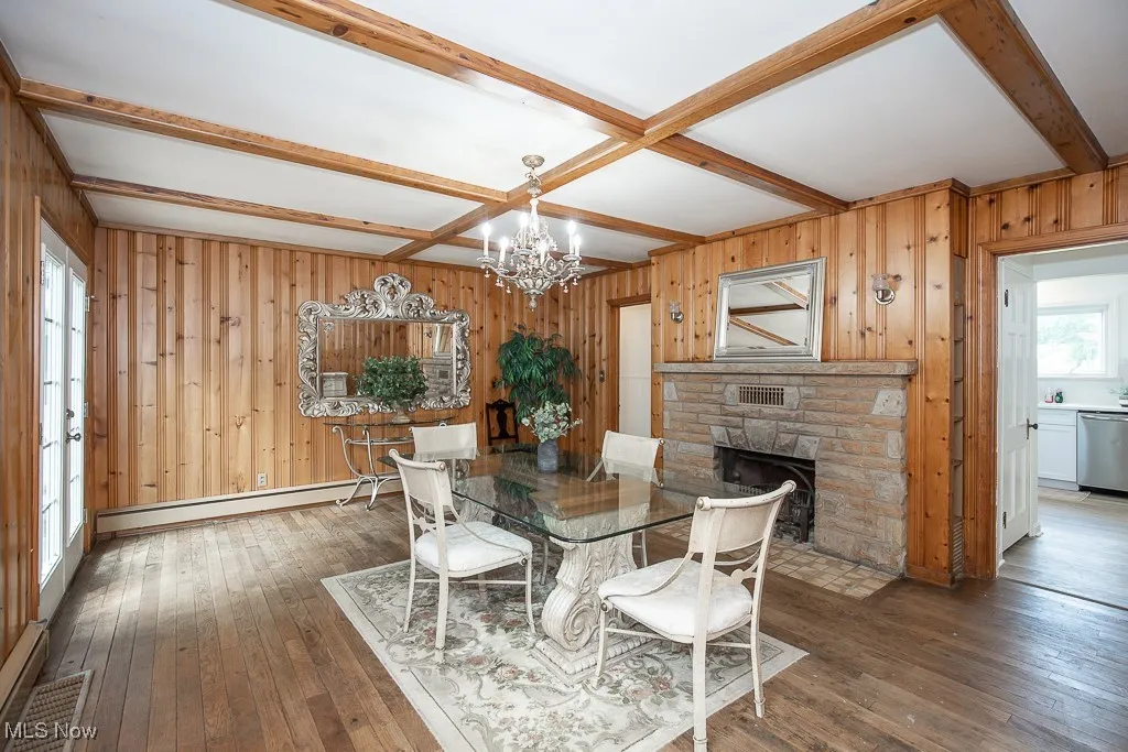 Dining space with a chandelier, hardwood / wood-style flooring, beamed ceiling, wooden walls, and coffered ceiling