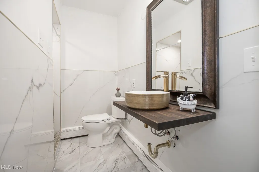Bathroom featuring marble look tiles, tile walls, and a baseboard radiator