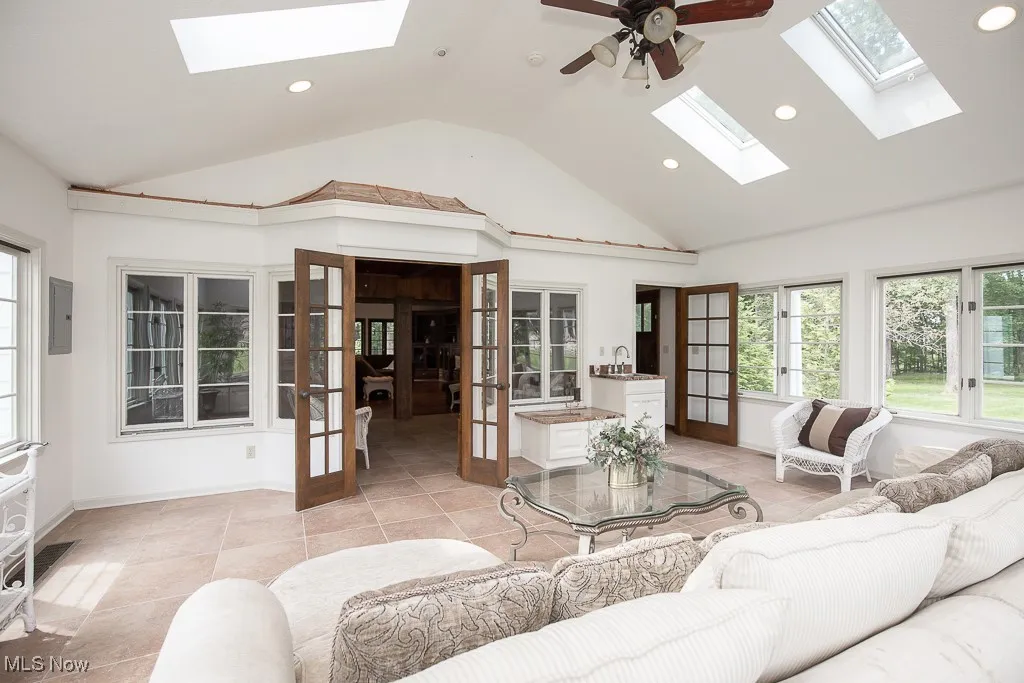 Living area with a skylight, recessed lighting, a ceiling fan, high vaulted ceiling, and light tile patterned flooring