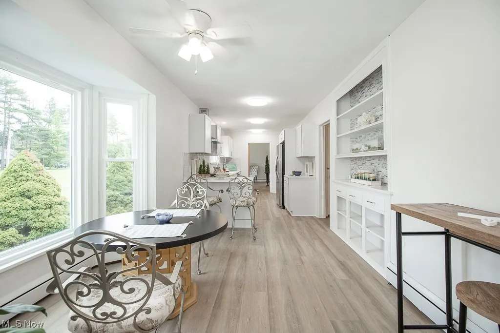 Kitchen featuring light wood finished floors, white cabinetry, ceiling fan, open shelves, and a baseboard radiator