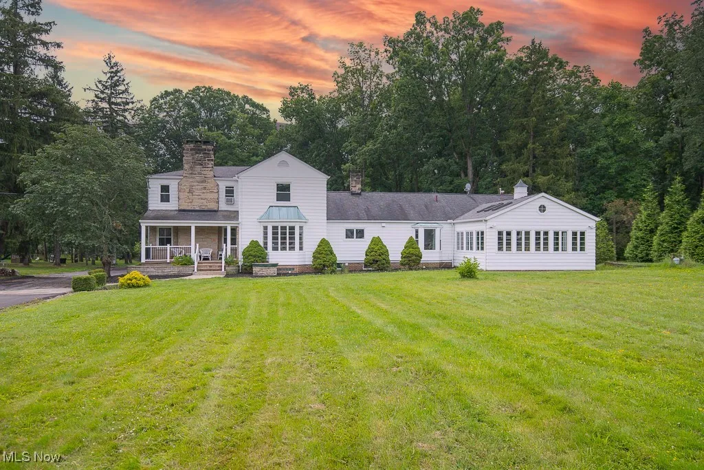 View of front of home featuring a porch, a chimney, and a yard