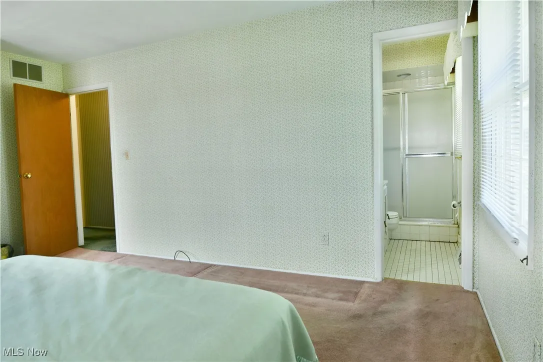 Carpeted bedroom with wallpapered walls and ensuite bathroom