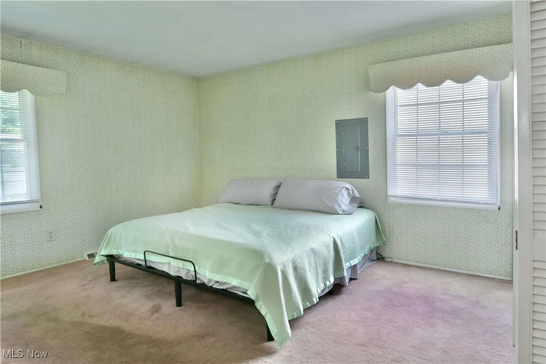 Bedroom with multiple windows, carpet, electric panel, and wallpapered walls