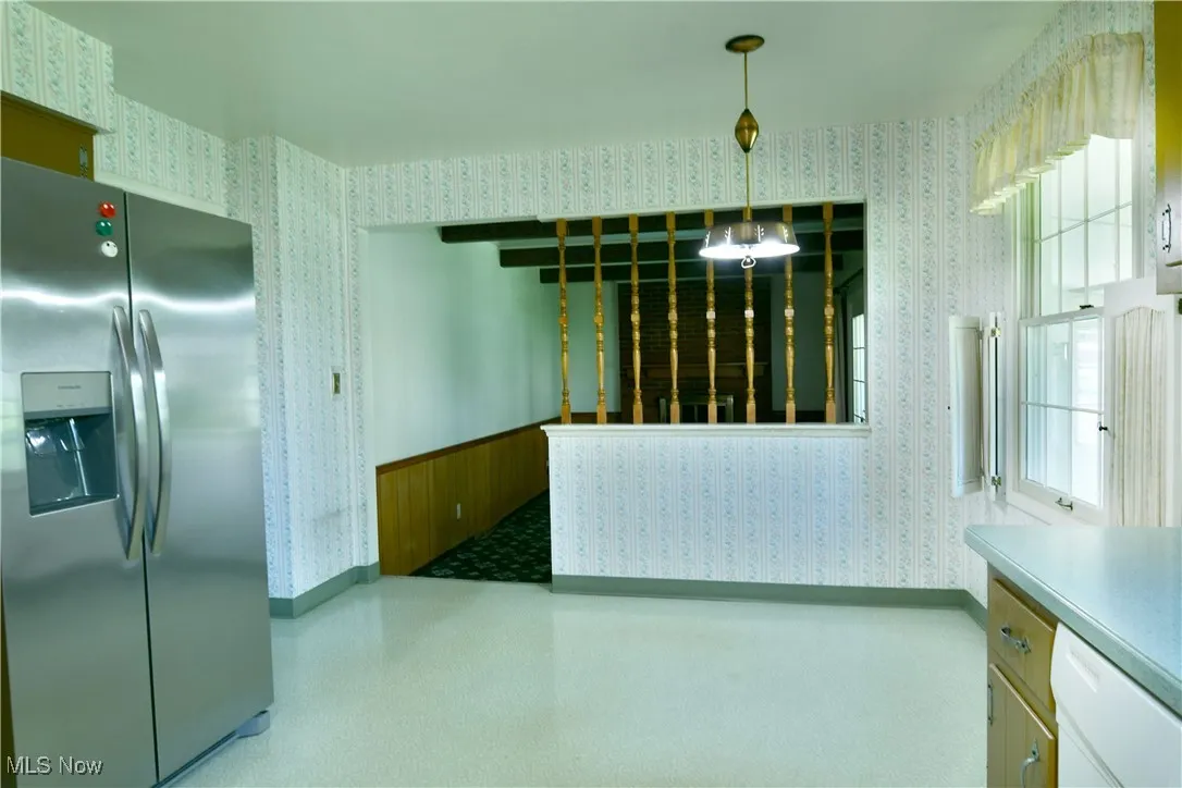 Unfurnished dining area featuring wallpapered walls and baseboards