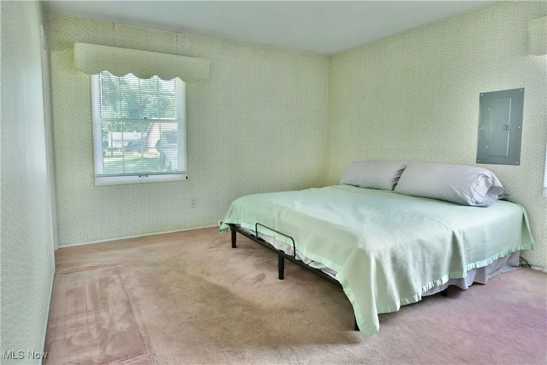 Bedroom featuring electric panel, carpet floors, and wallpapered walls