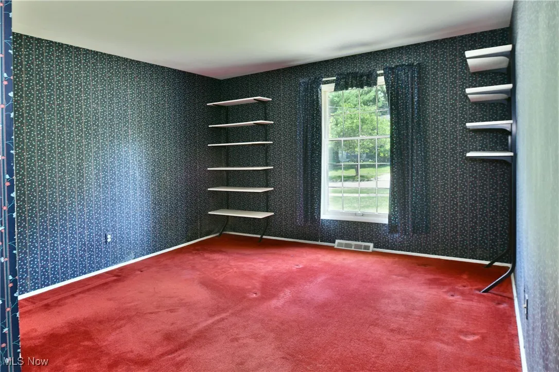 Empty room with wallpapered walls and carpet flooring