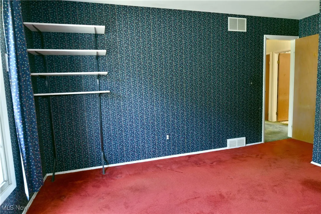 Carpeted empty room featuring wallpapered walls