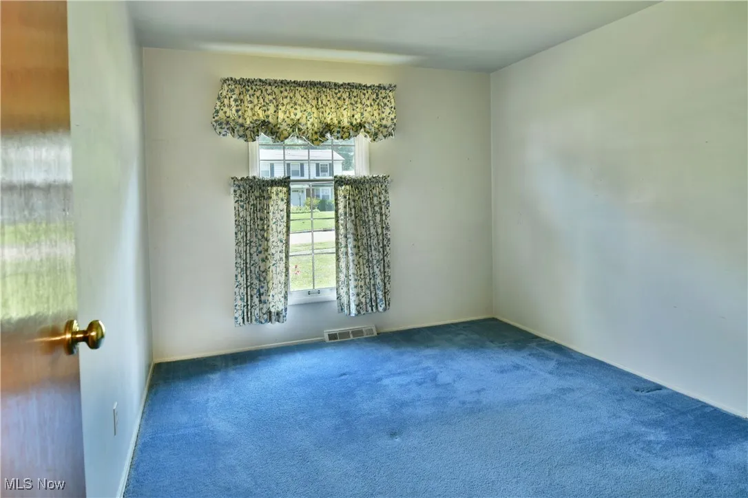 Carpeted spare room featuring baseboards