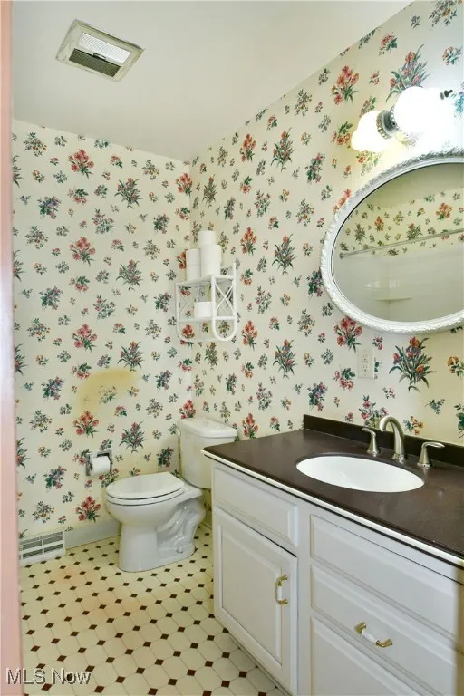 Half bathroom with wallpapered walls and vanity