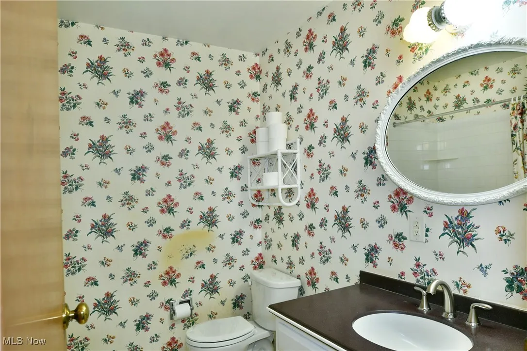 Half bath with wallpapered walls and vanity