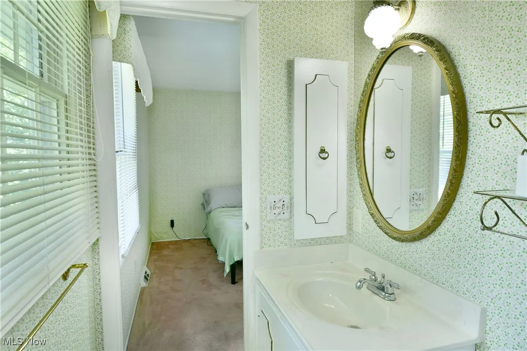 Ensuite bathroom with wallpapered walls and vanity