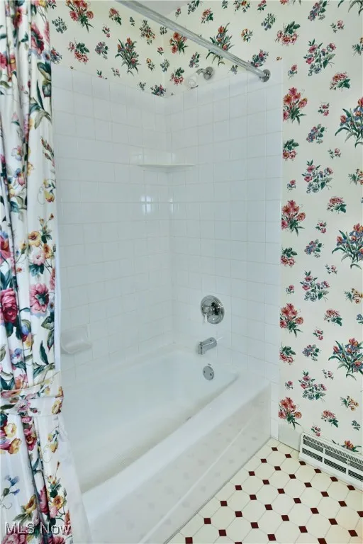 Full bath with wallpapered walls, a baseboard radiator, and shower / tub combo