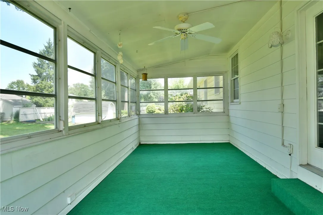 Unfurnished sunroom with ceiling fan and vaulted ceiling