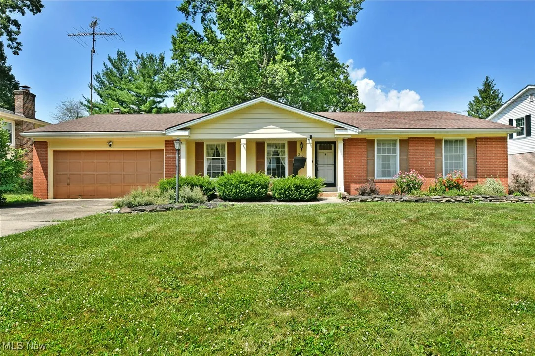 Ranch-style house featuring a garage, concrete driveway, brick siding, a front yard, and covered porch
