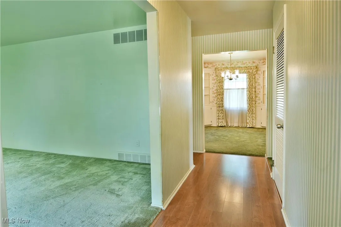 Corridor with a chandelier, carpet floors, and wood finished floors