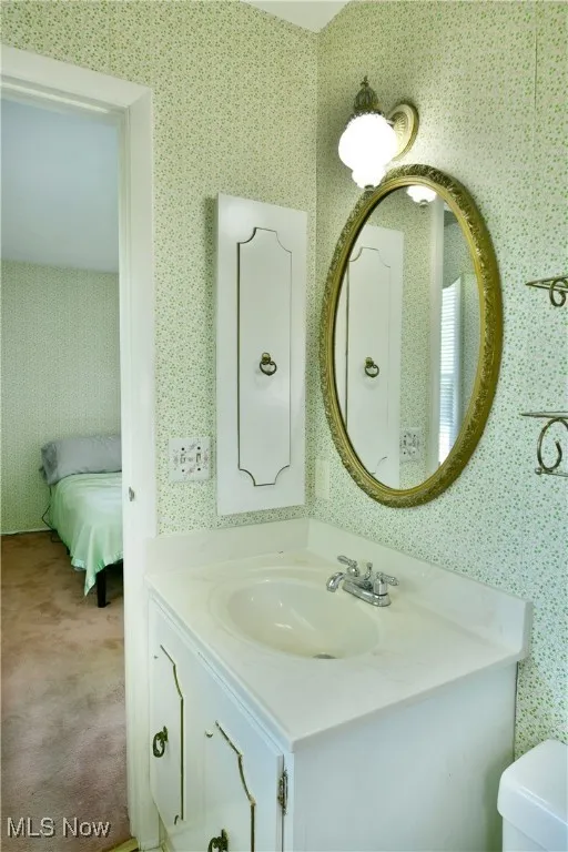 Bathroom featuring wallpapered walls and vanity