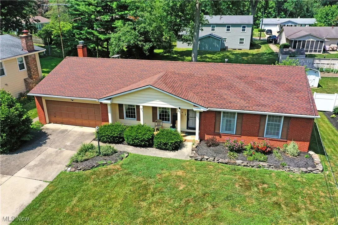 View of front of home featuring brick siding, concrete driveway, an attached garage, a chimney, and roof with shingles