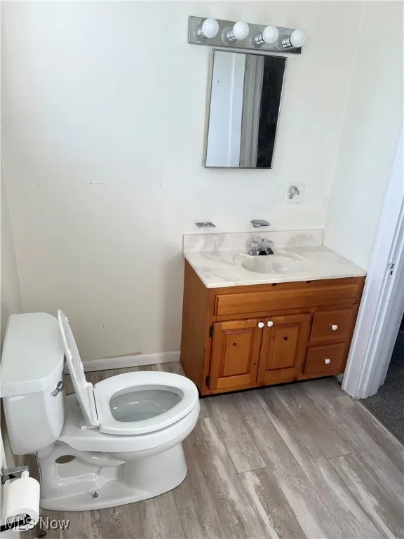 Upstairs bathroom with vanity, toilet, and wood finished floors.