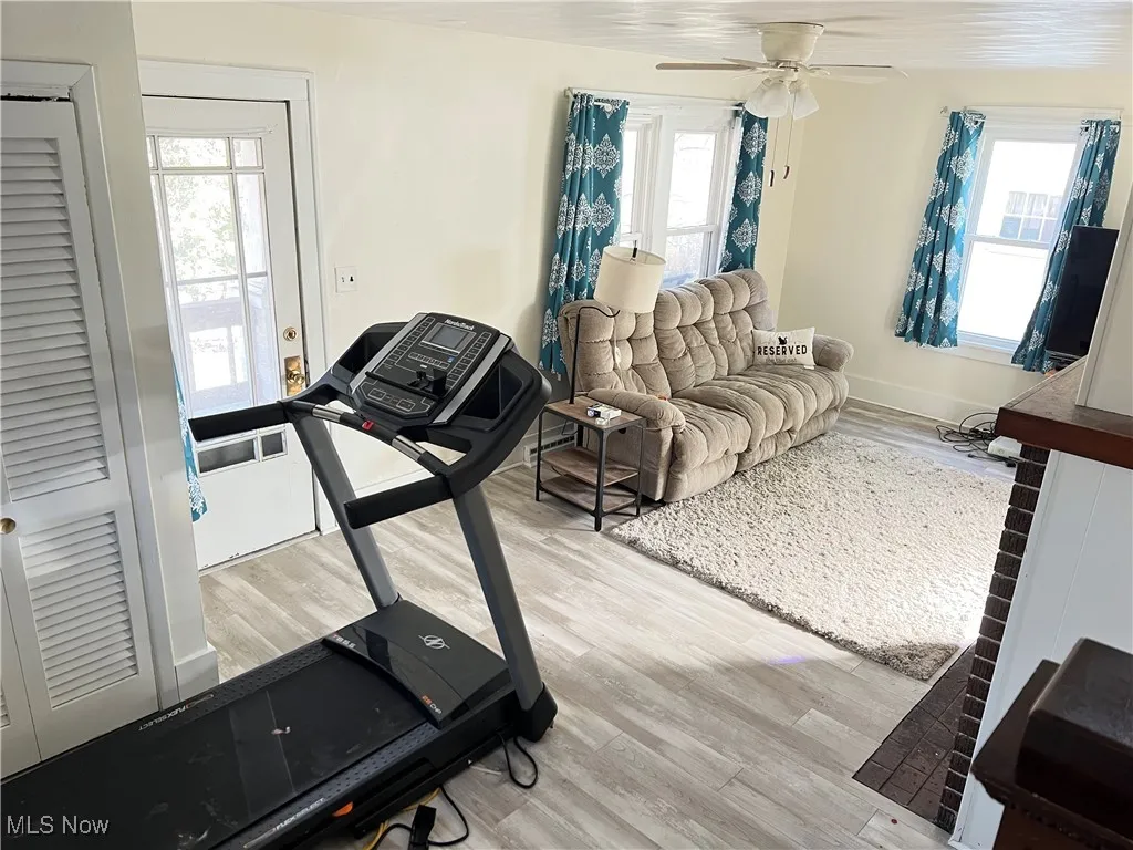 Exercise room with wood finished floors, baseboards, and ceiling fan