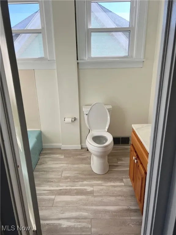 Upstairs bath featuring a wealth of natural light, toilet, and wood finished floors.