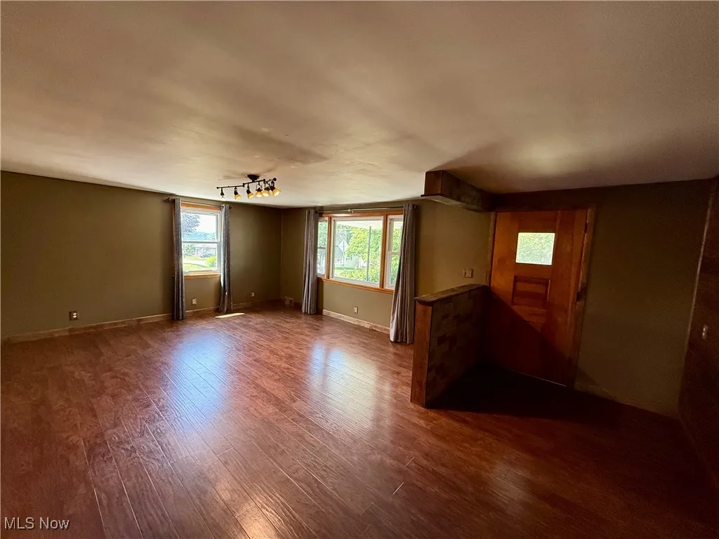 Spare room featuring dark wood-style flooring and baseboards