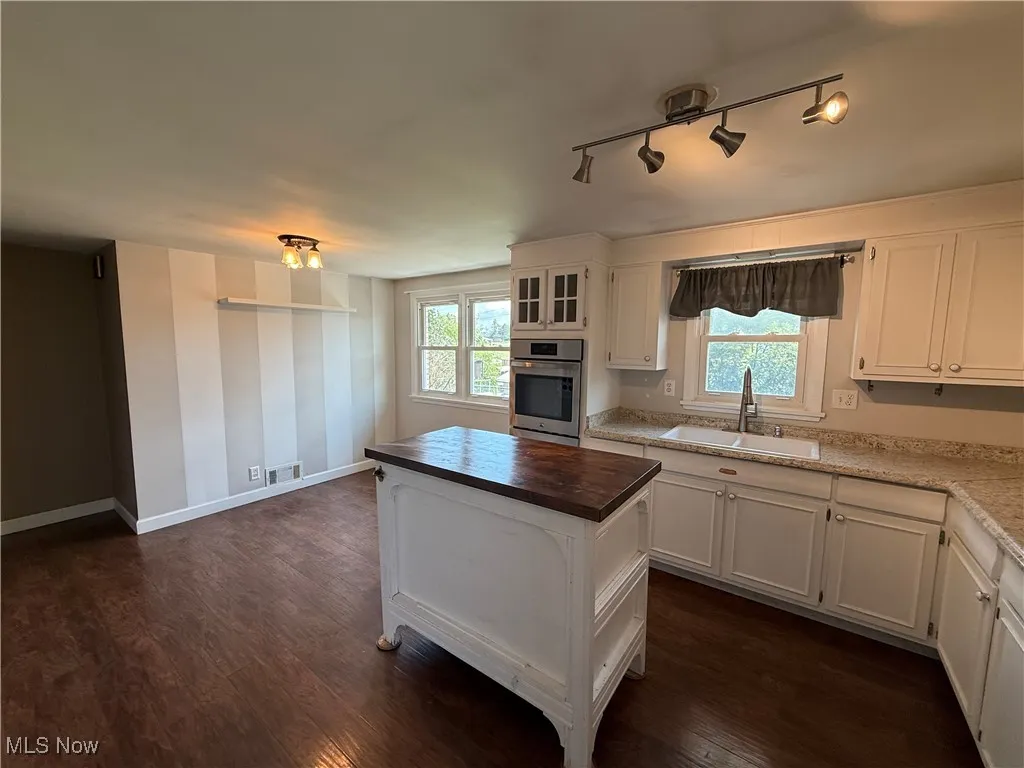 Kitchen with oven, white cabinetry, and dark wood-style flooring