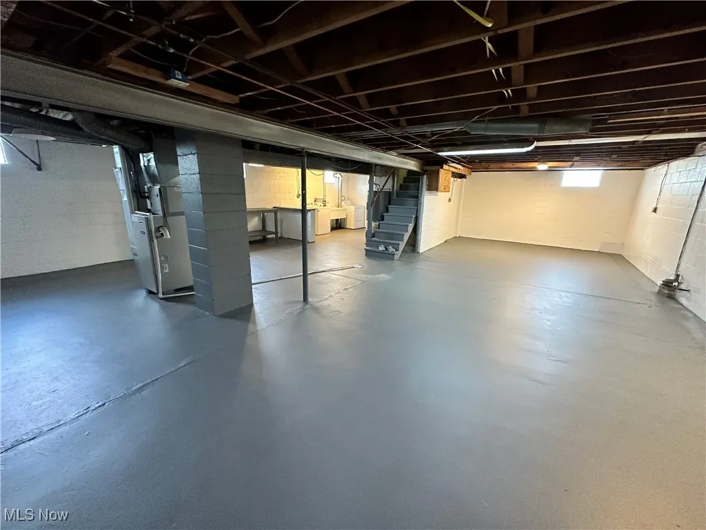 Basement featuring stairs, concrete block wall, and heating unit