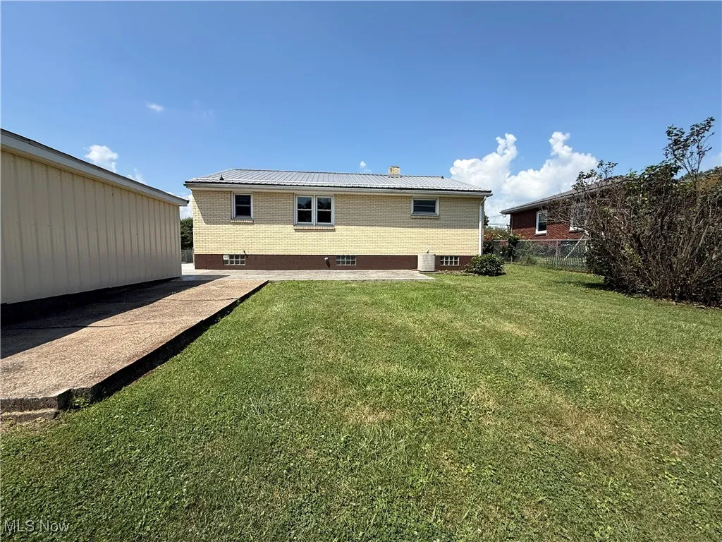 Rear view of house featuring brick siding and a metal roof