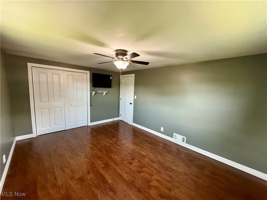 Unfurnished bedroom with dark wood-style floors and ceiling fan