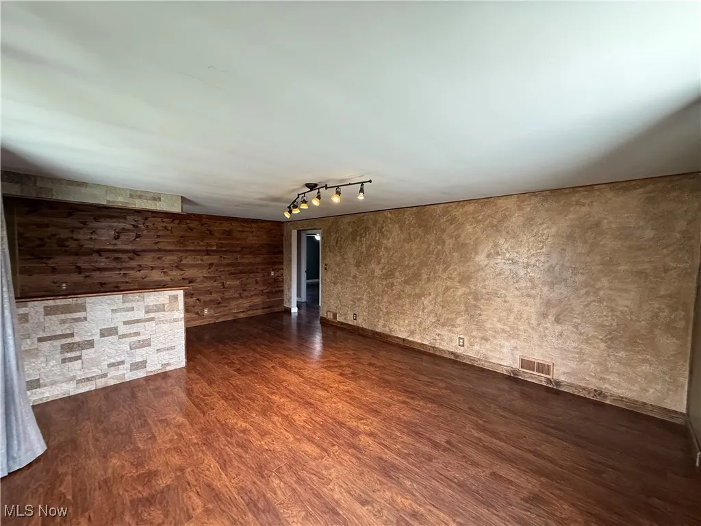 Spare room with dark wood finished floors and track lighting