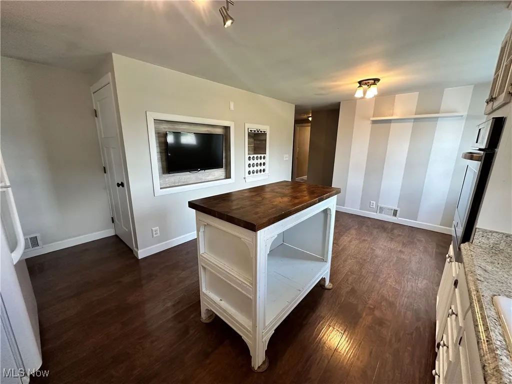 Kitchen featuring butcher block counters, stainless steel oven, dark wood-type flooring, and white cabinets