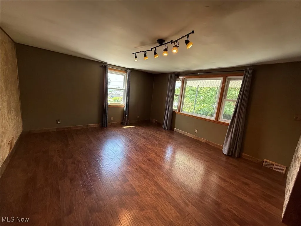 Empty room with dark wood-style flooring and baseboards