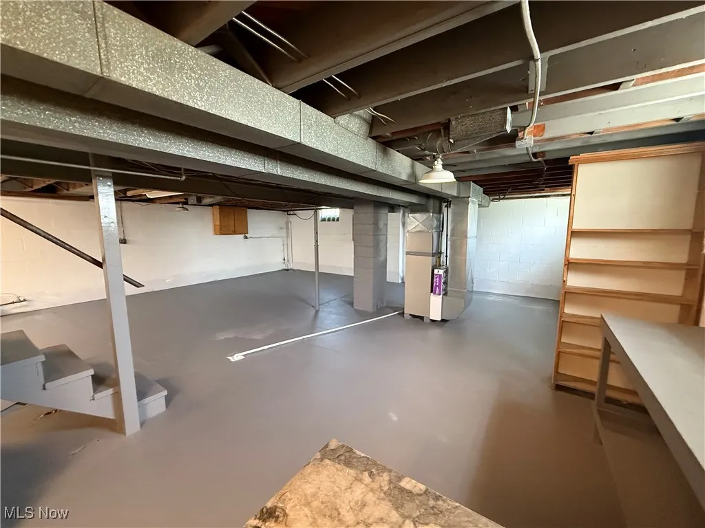 Unfinished basement with heating unit and stairs