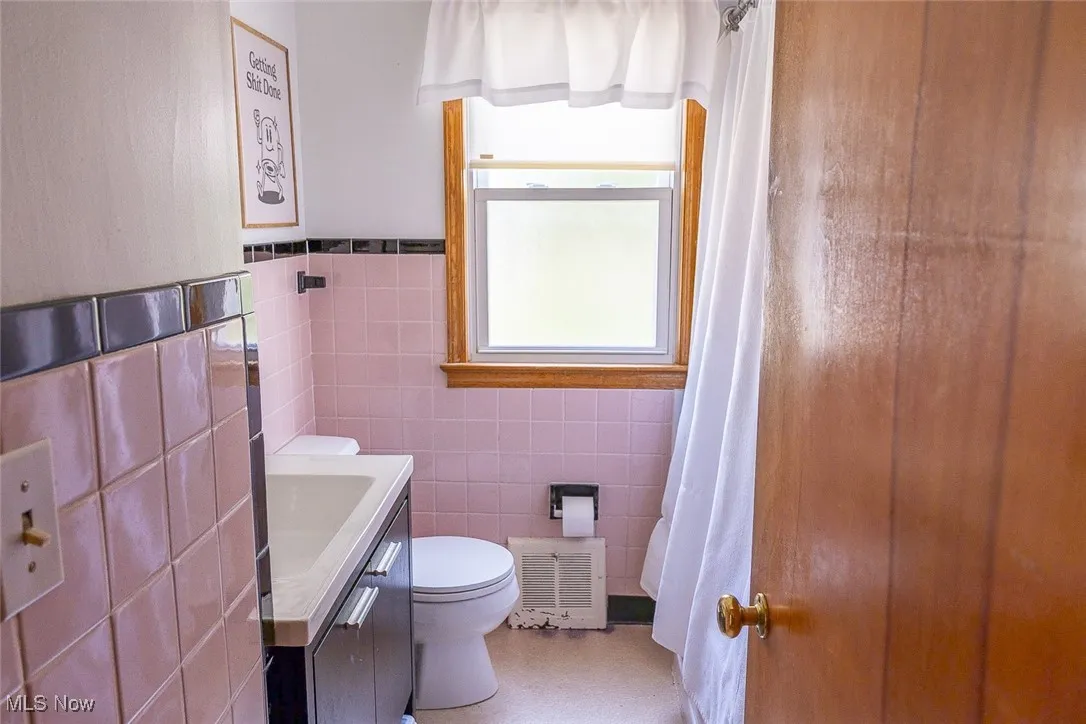 Bathroom with tile walls, vanity, and a shower with curtain