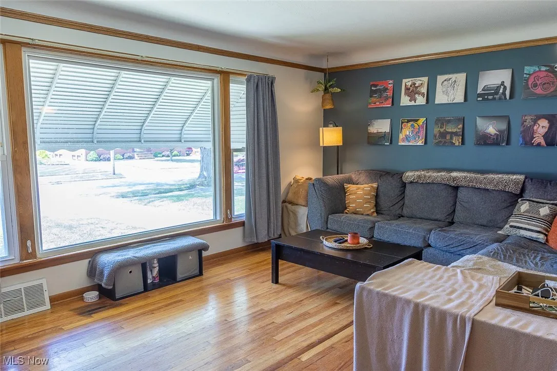 Living area featuring light wood-type flooring and ornamental molding