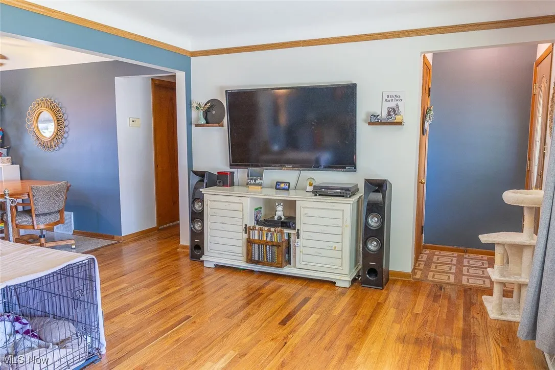 Living room with wood finished floors and ornamental molding