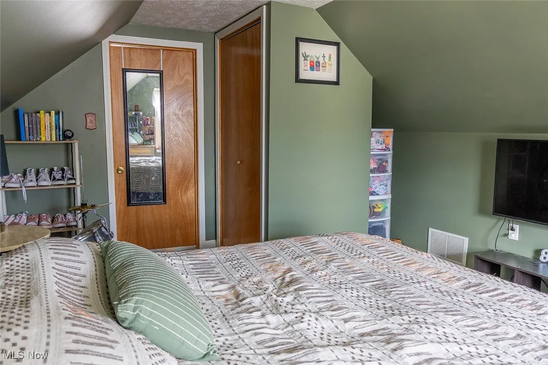 Bedroom three featuring vaulted ceiling, a closet