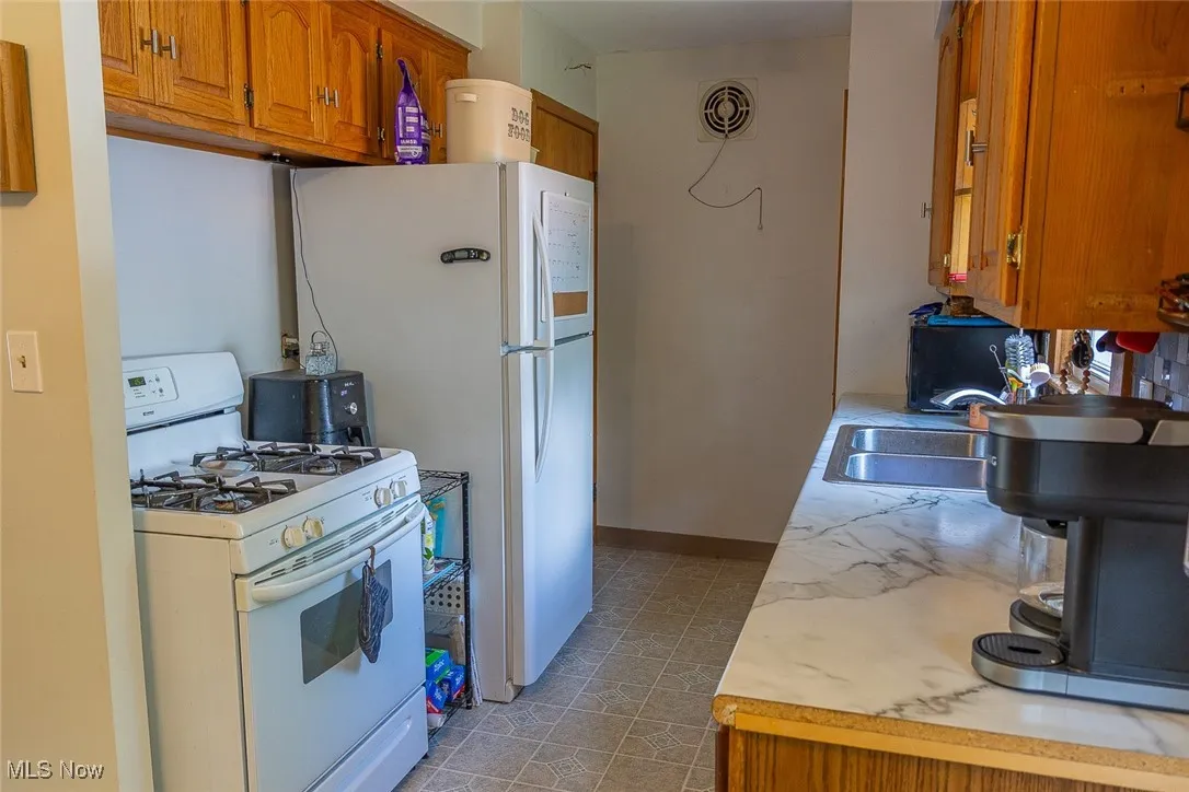 Kitchen featuring white appliances, light countertops, and brown cabinetry