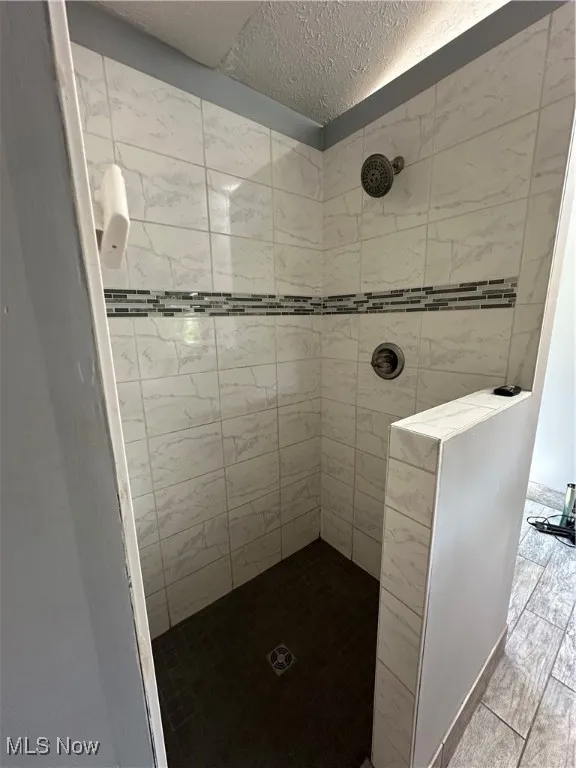 Bathroom with a textured ceiling and a tile shower